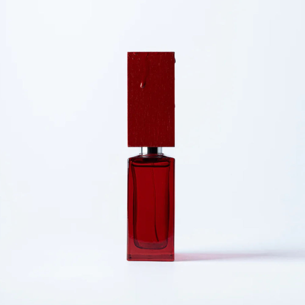 A rectangular red glass perfume bottle with a matching red cap, standing upright on a clean white background.