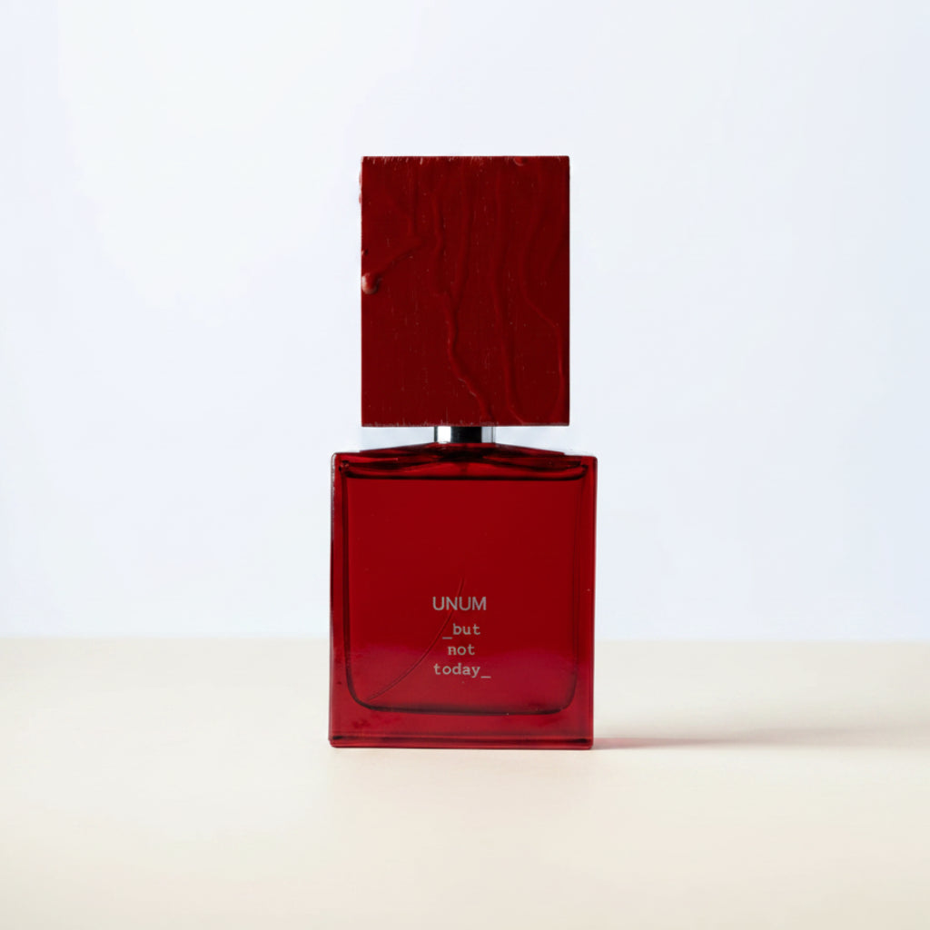A red rectangular perfume bottle with a matching red cap, featuring the brand name 'UNUM' and scent name 'Rosemary' printed in white on the front, set against a plain white background.
