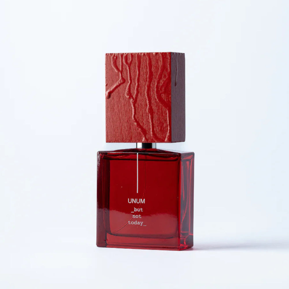 Red perfume bottle with wooden cap on a white background
