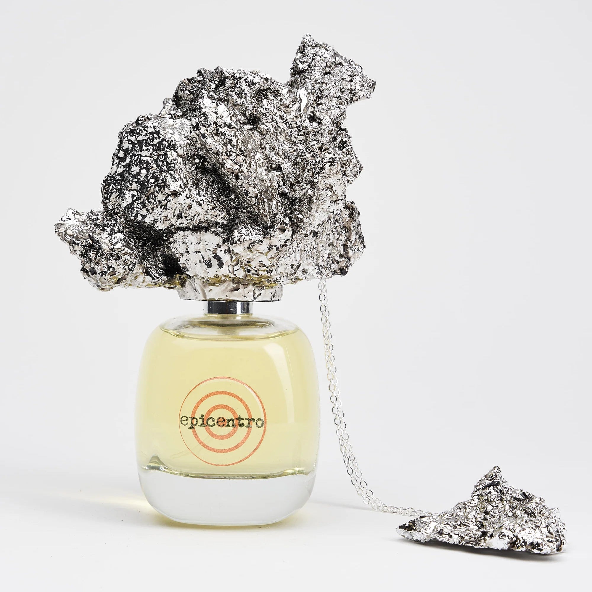 Perfume bottle with decorative rock-like elements on a white background