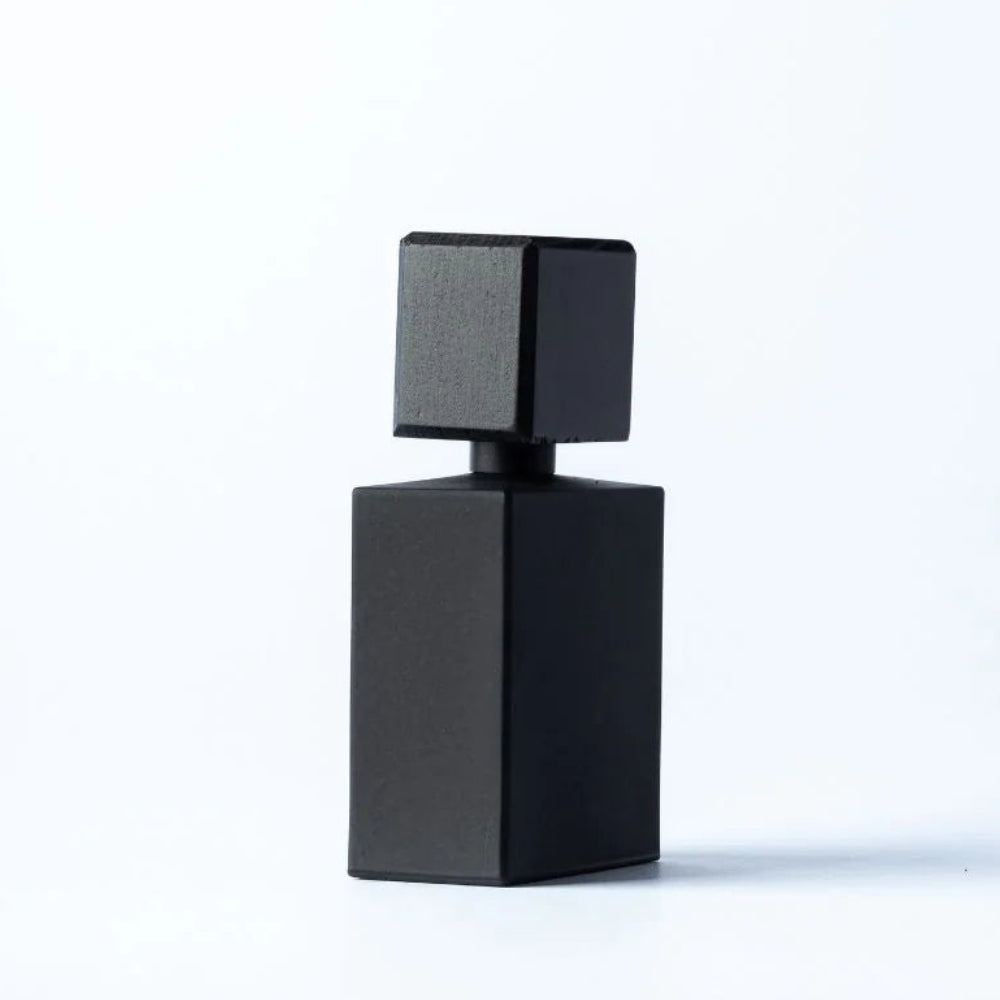 A minimalist black geometric perfume bottle with a square top and a rectangular base, centered on a clean white background.